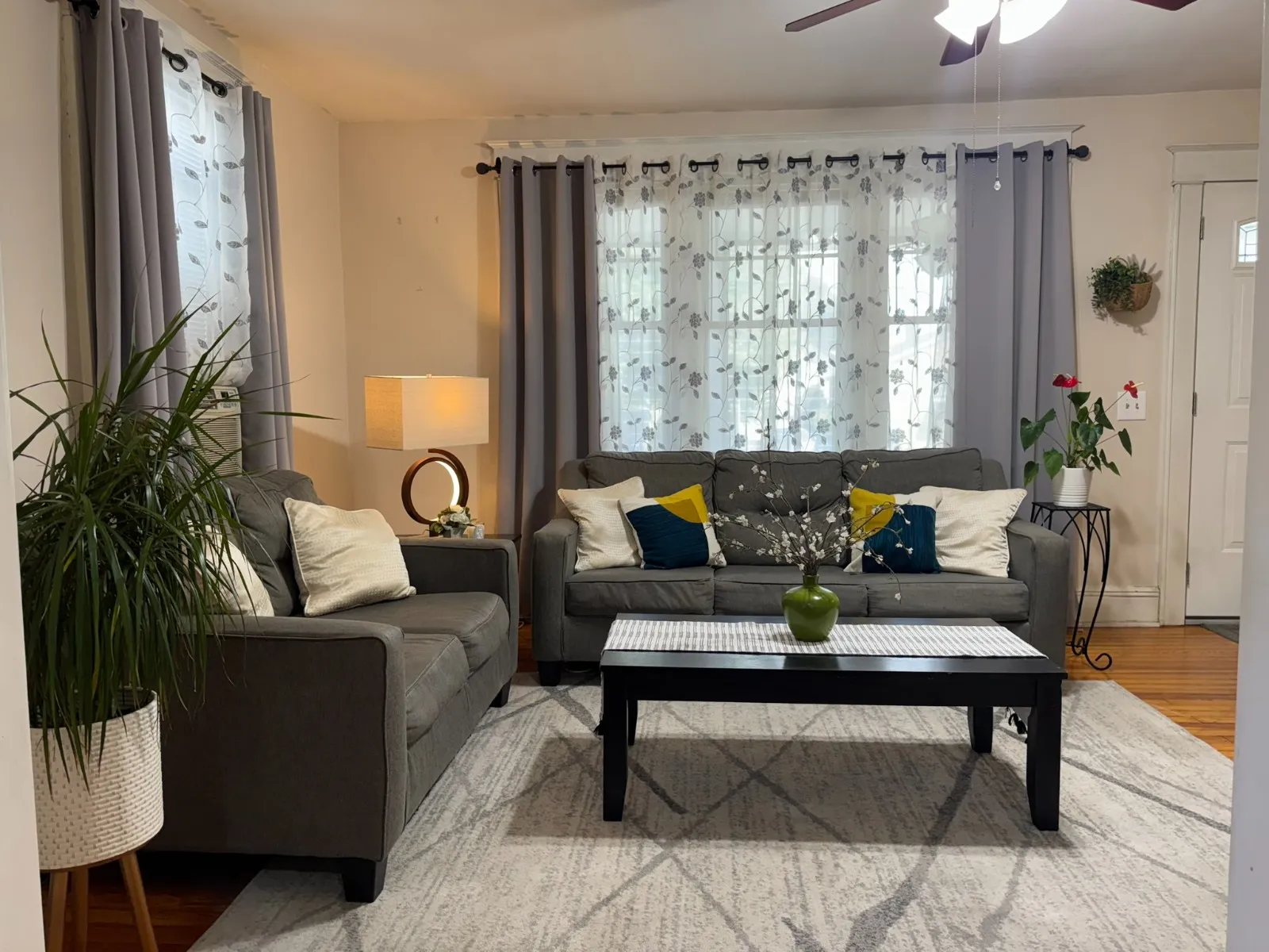 Living room after restyling by Kultur & Decor: living room, warm evening light: staged gray sofas, styled coffee table, anthurium.